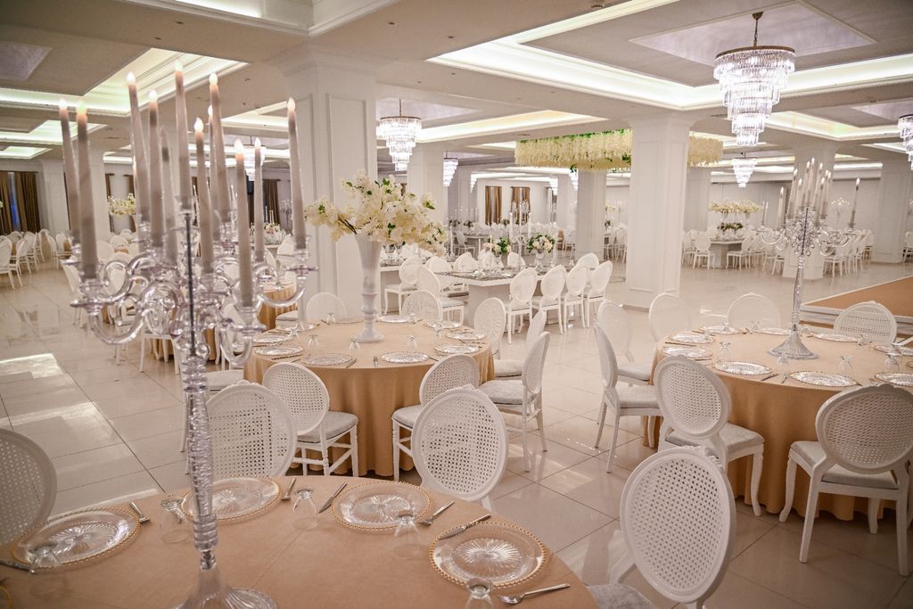 Kristal şamdanlar ve yuvarlak davet masalarıyla hazırlanmış geniş kapalı salon.