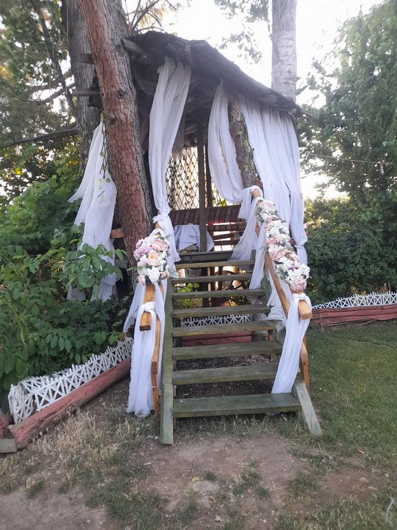 Ağaç evi andıran, beyaz tüller ve çiçeklerle süslenmiş ahşap kamelya.