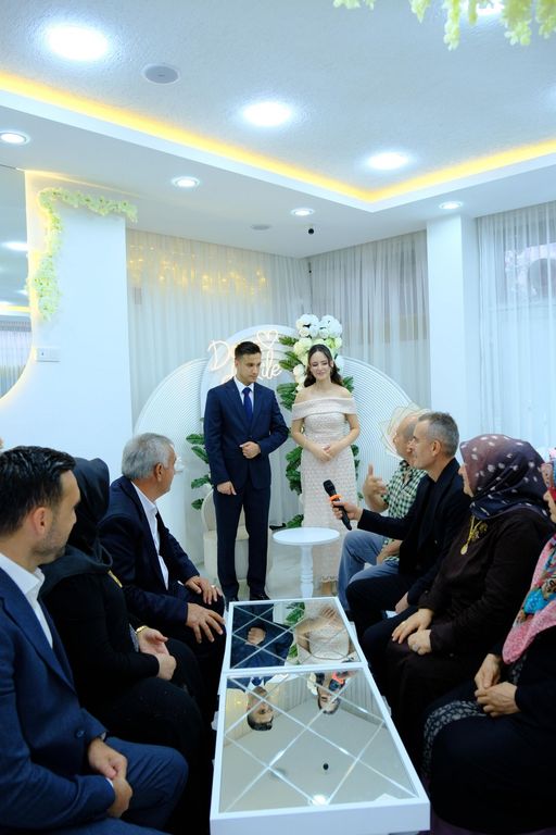 Söz töreni sırasında ayakta duran çift ve konuşma yapan aile büyükleri.