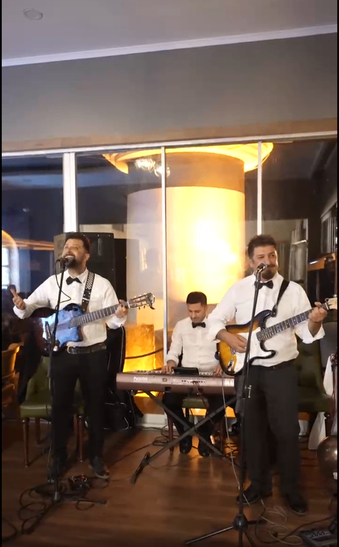 Sahnede gitar ve klavye eşliğinde şarkı söyleyen canlı müzik grubu.