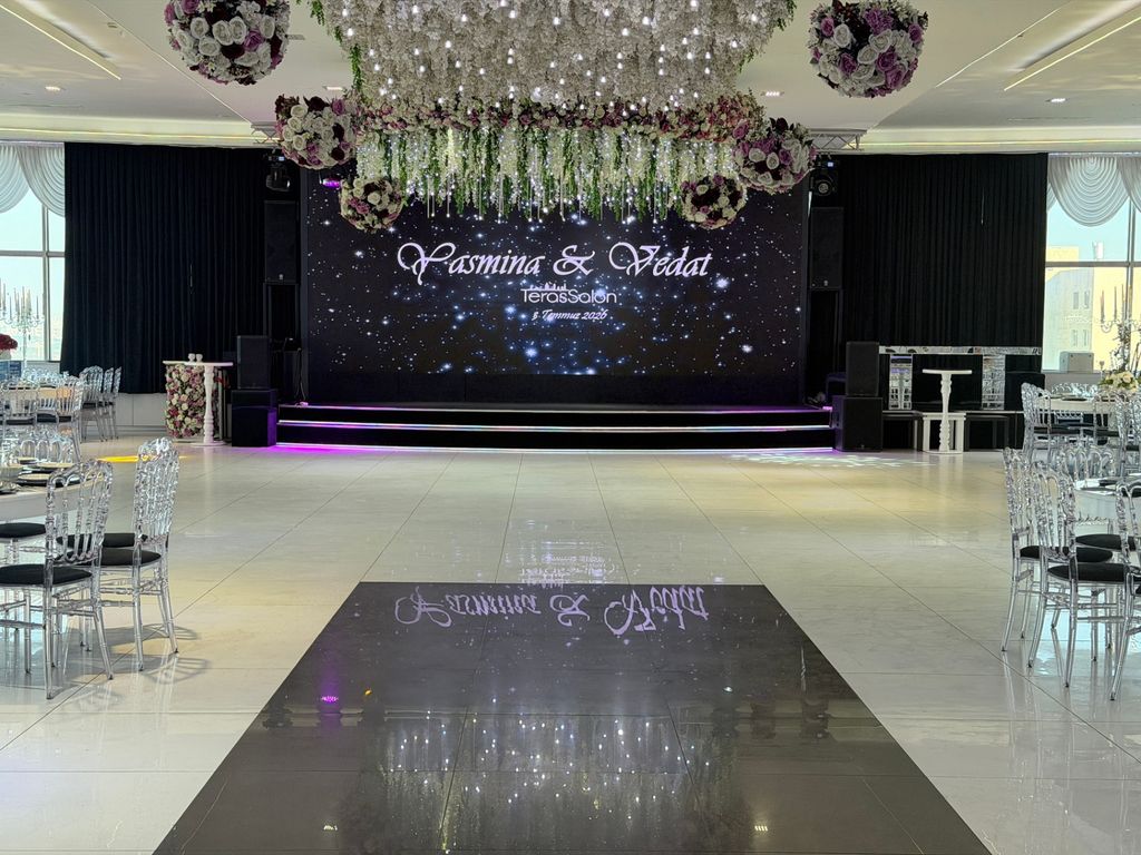 LED ekranlı sahnesi, dans pisti ve sarkan çiçekli tavanı bulunan salon.