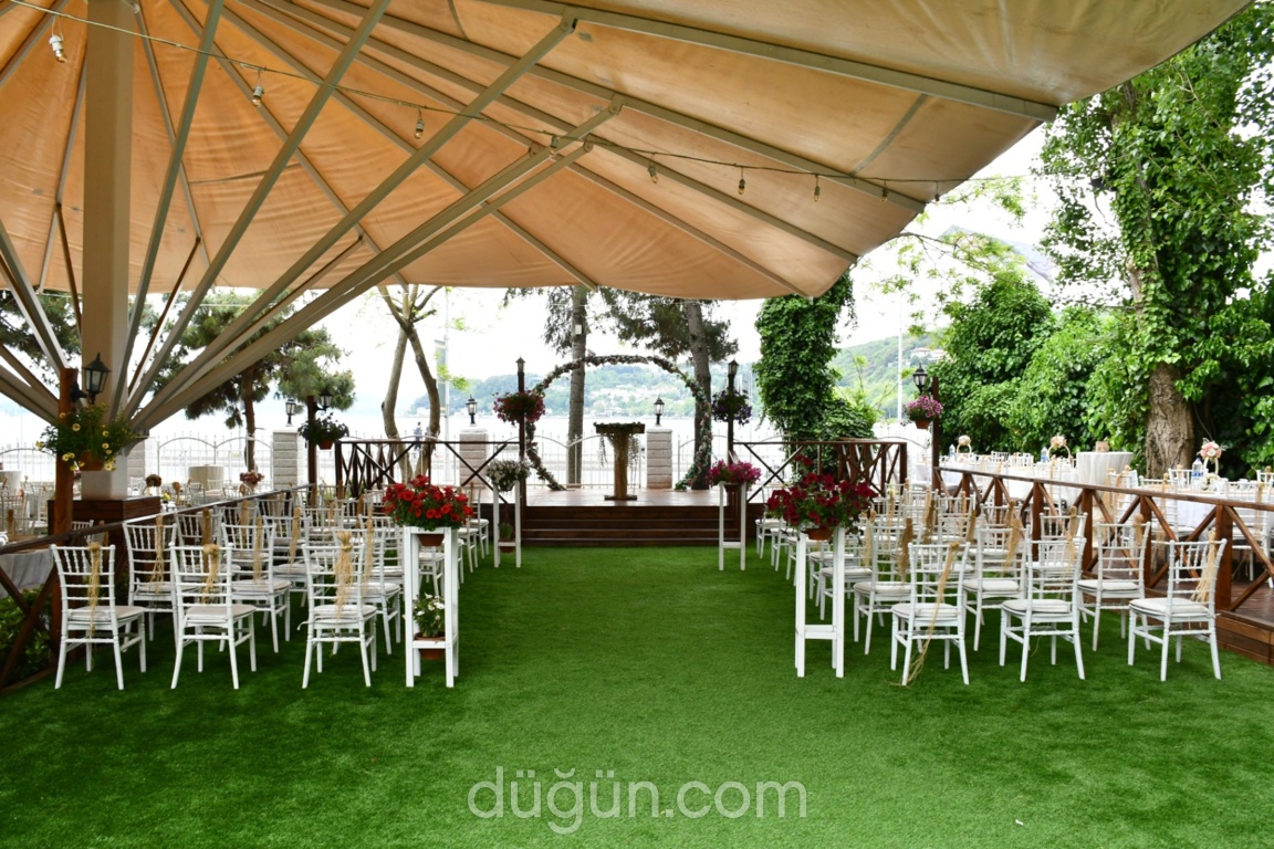 Tente altında sıralanmış beyaz sandalyeler ve ahşap nikah platformu.