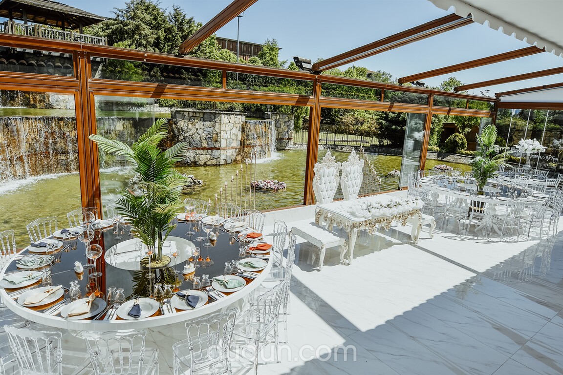 Yapay şelaleye bakan cam salonda gelin damat masası ve davet alanı.