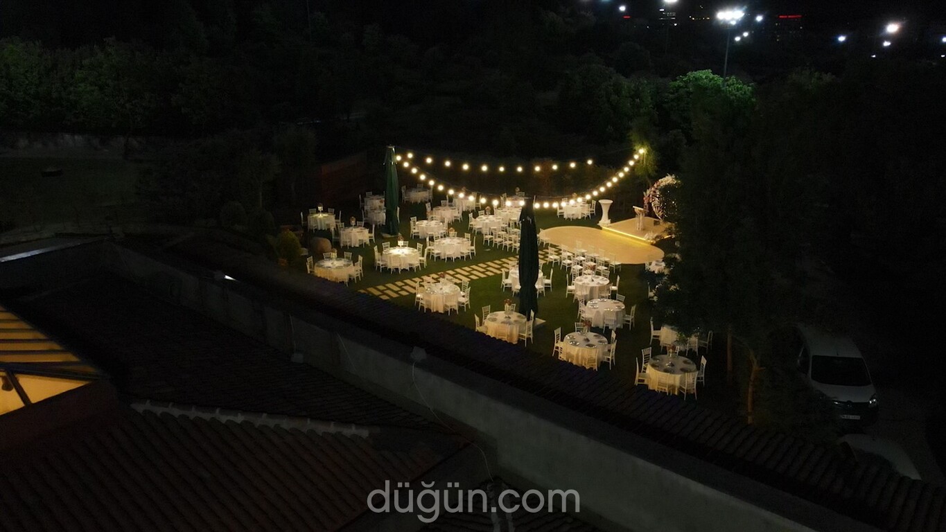 Gece ışıklandırması altında bahçede kurulu davet masaları ve dans pisti.